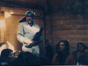 A man is standing in front of a group of people in a cabin.