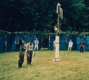 A group of people standing around a pole in a field.