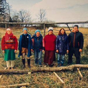 A group of people standing in a field with logs.