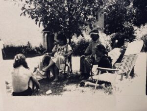 A black and white photo of a group of people sitting under a tree.