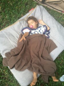 A child laying on a blanket in the grass.