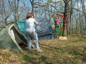 Two women standing next to a tent in the woods.