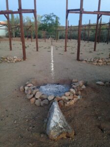 A fire pit in the desert with a rock in the middle.
