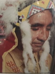 A photo of an indian man wearing a feathered headdress.