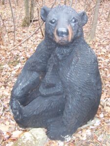 A black bear statue in the woods.