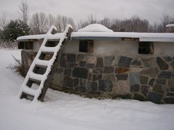 A stone building covered in snow with a ladder.